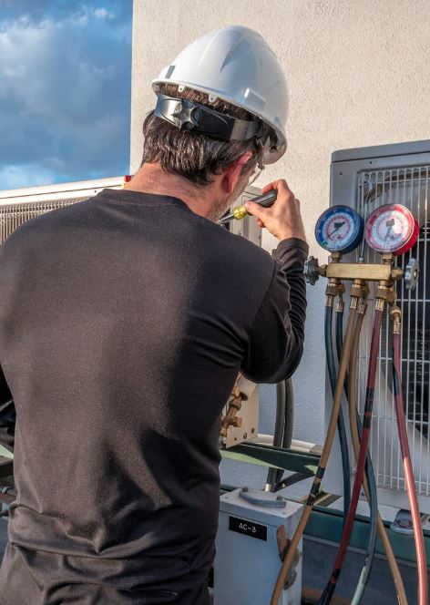Technician repairing outdoor AC unit with tools.