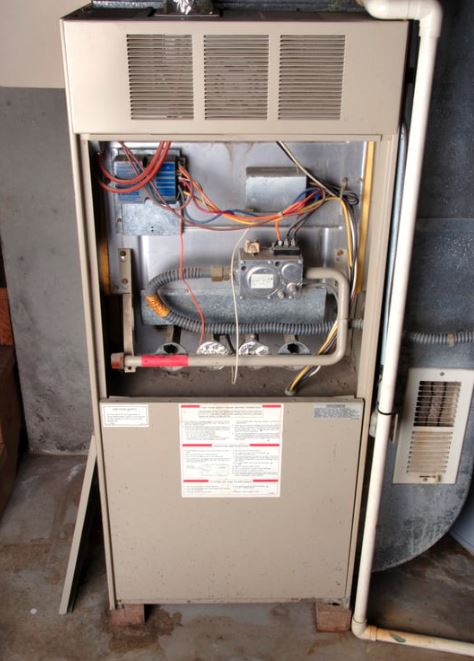 Old gas furnace with exposed wiring and components.